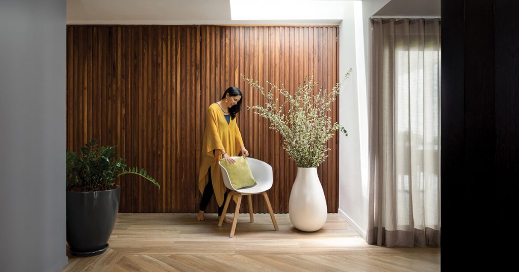 Interior con muro de madera, silla y arreglo floral en un espacio diseñado por Mariangel Coghlan.